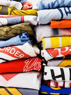 A stack of many colorful t-shirts that have been aged using various techniques.