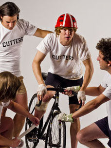 Group Costume guide for the Cutters bike riders from the movie Breaking Away.  The four cyclists are wearing white tee shits that say "Cutters," bike shorts, and riding gloves.