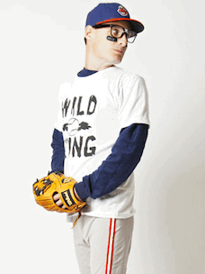 Costume guide for Ricky Vaughn from the movie Major League.  Ricky wears a blue and red baseball cap, black glasses, a white t-shirt that says "Wild Thing" in black lettering, and grey baseball pants with red stripes down the side.  He holds a brown baseball glove.