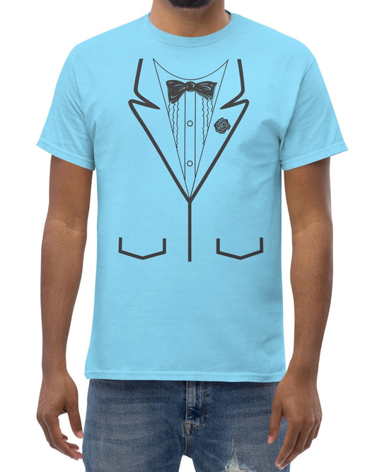 A man wearing a light blue crewneck t-shirt with a black line art graphic of a tuxedo jacket on the front, paired with blue jeans against a plain white background.